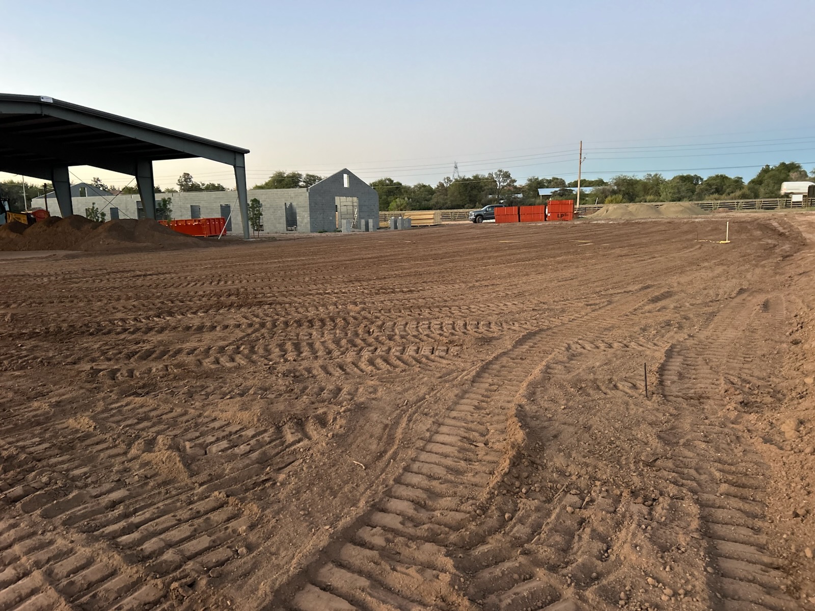 Prescott AZ Arena Pad & Covered Build Freshly graded outdoor riding arena pad in Prescott, Arizona next to a steel covered arena and barn under construction